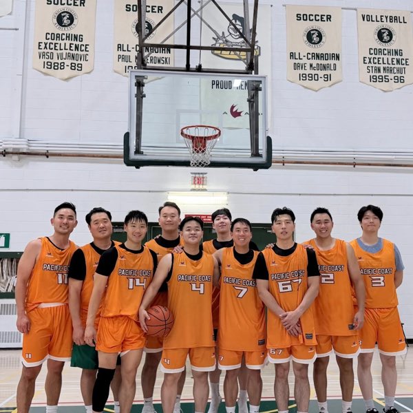 The Pacific Coast squad in orange jerseys, gathered under championship banners.